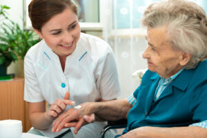 Young female creamer helps senior woman with hand cream