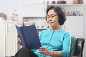 Senior Asian woman reading book at home